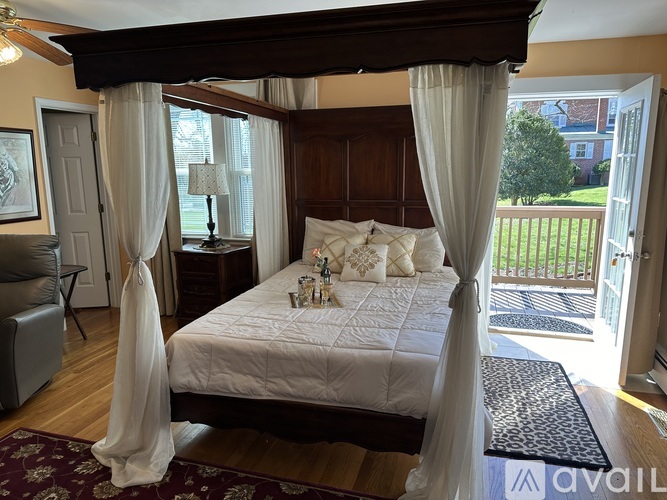 A bedroom with a canopy bed and a view of a backyard.