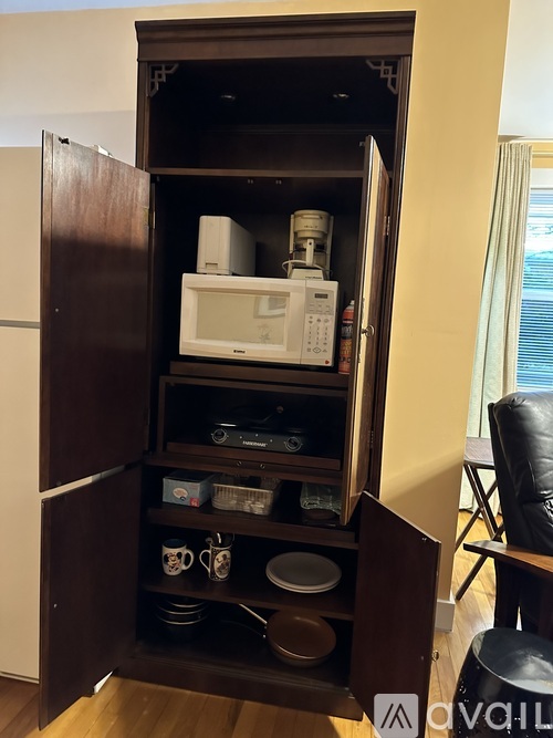 A microwave oven is sitting on a shelf in a kitchen cabinet.