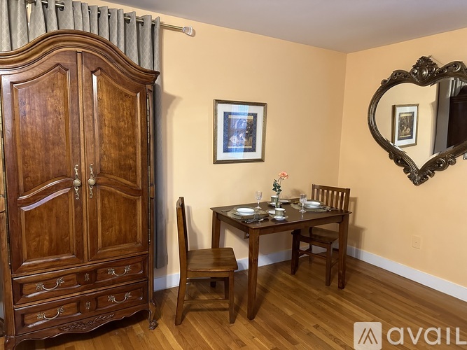 A wooden dining table with chairs and a cabinet in a room.