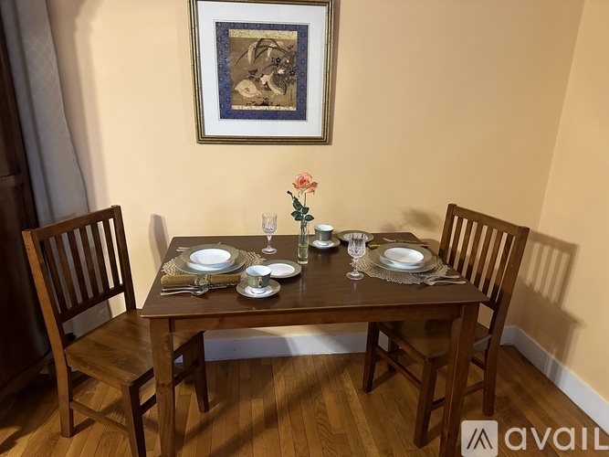 A dining table set with plates and glasses with a painting hanging on the wall.
