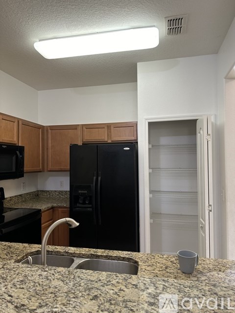 A kitchen with a black refrigerator and a sink.