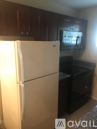 A white refrigerator is in a kitchen with brown cabinets.