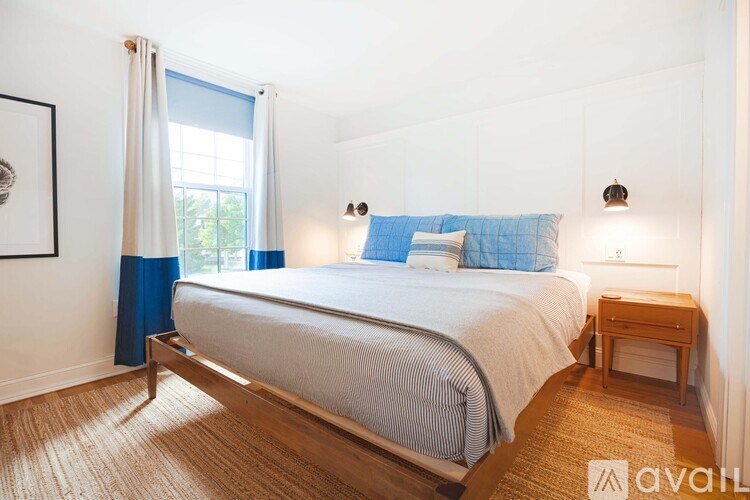 A bedroom with a bed, nightstand, and window.