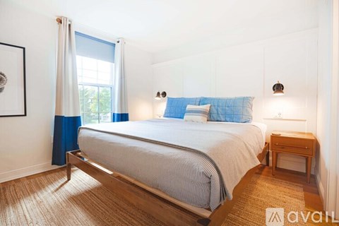 A bedroom with a bed, nightstand, and window.