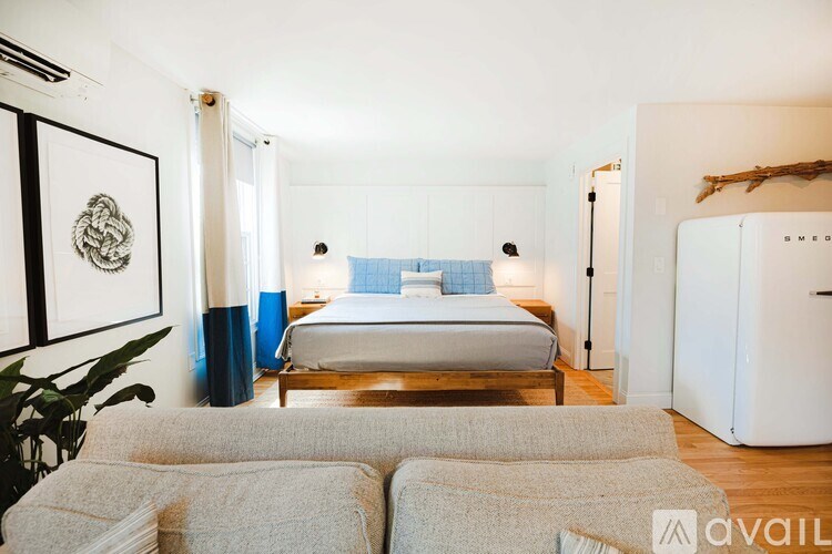 A bedroom with a bed, a couch, and a painting on the wall.