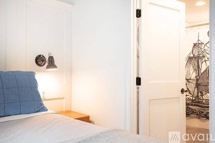 A bedroom with a bed, nightstand, and lamp.