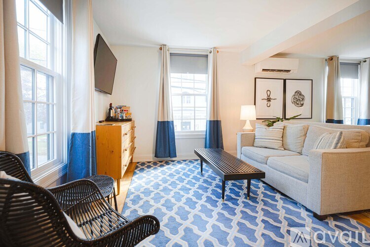 A living room with a white couch, a wooden coffee table, and a television.