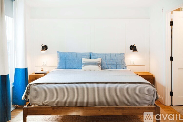 A bed with blue pillows and a grey bedspread is in the image.