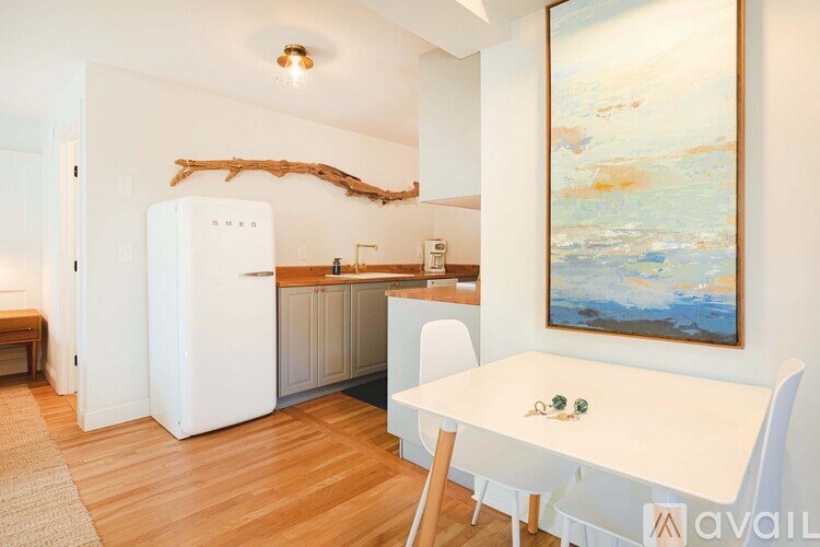 A kitchen with a white table and chairs and a painting on the wall.