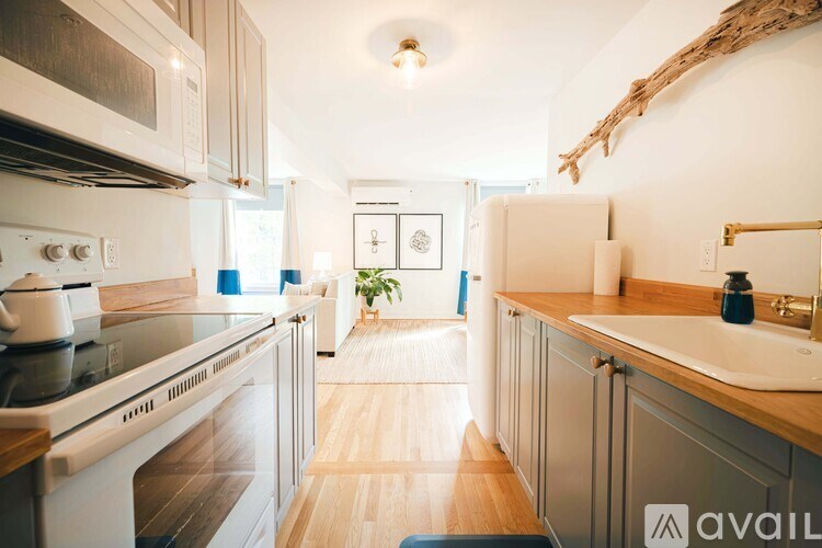 A kitchen with a white stove top oven and a white sink.