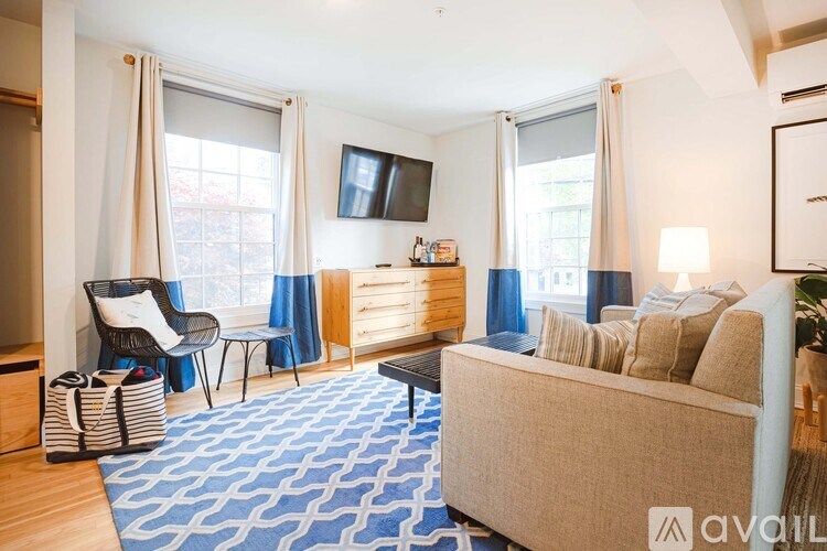 A living room with a beige sofa, a chair, and a TV mounted on the wall.