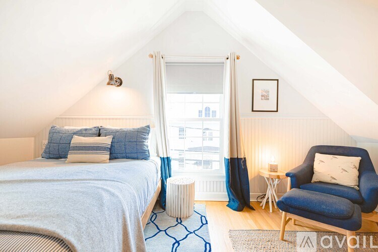 A bedroom with a bed, a chair, and a window.