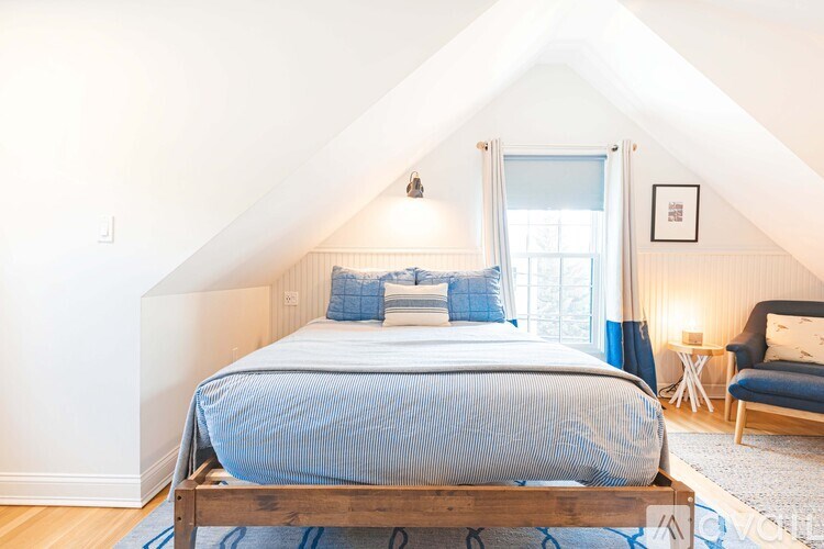 A bedroom with a bed and a chair.