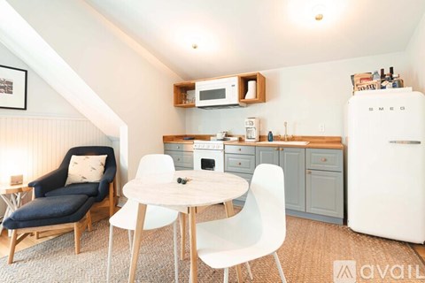 A kitchen with a white fridge, a table with chairs and a sofa.