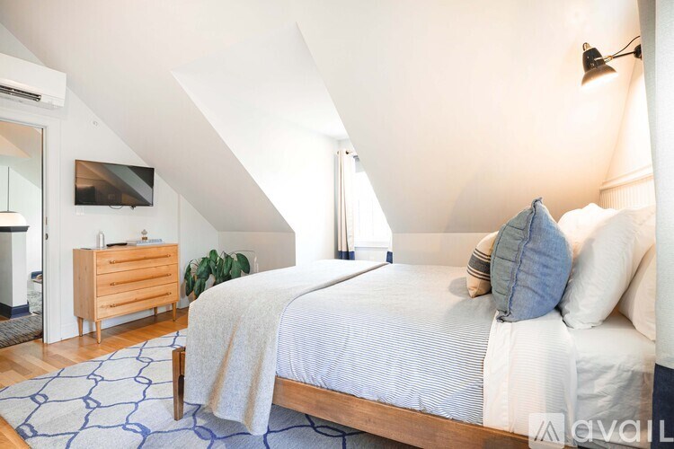 A bedroom with a bed, pillows, and a wooden dresser.