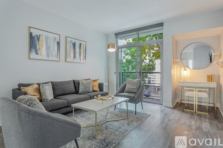 A living room with a grey couch, a grey armchair, a white coffee table, and a round mirror on the wall.