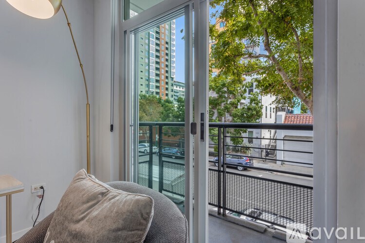 A chair with a cushion is in front of a window with a view of a city street.