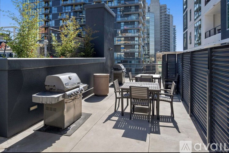 A patio with a grill and chairs overlooking a city.