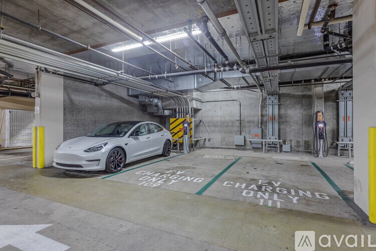 A white Tesla car is parked in a parking garage.