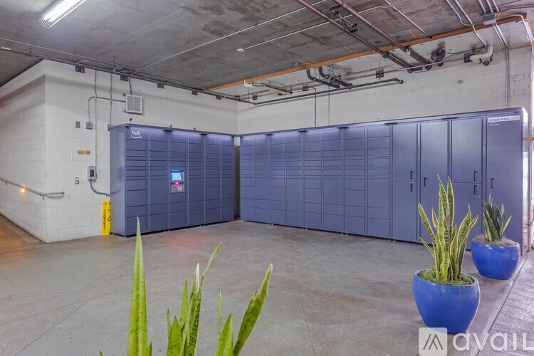 A room with a white wall, a grey floor, and a blue cabinet.