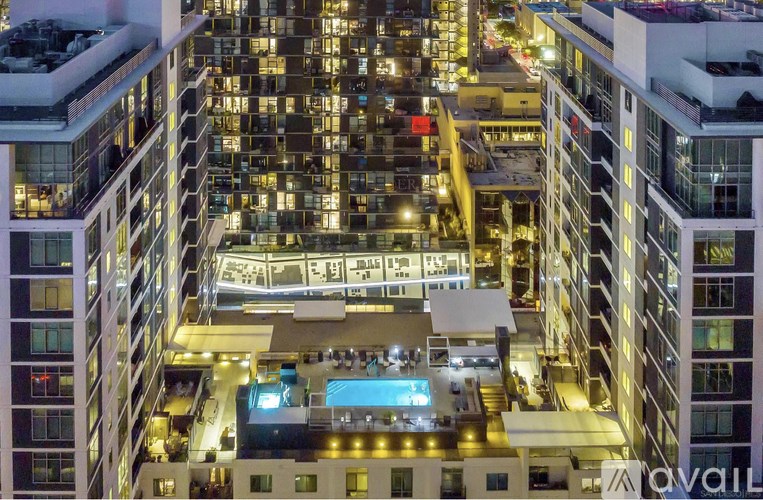 A cityscape at night with a lit up pool in the foreground.