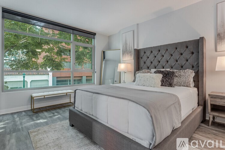A bedroom with a large bed and a window overlooking a balcony.