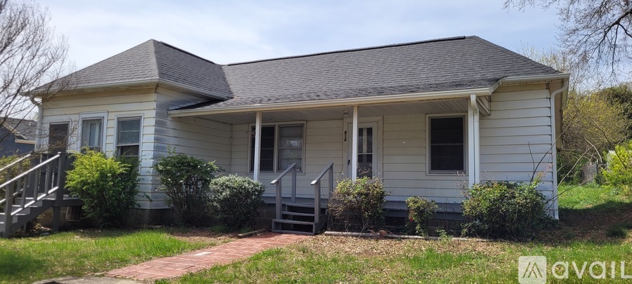 A small house with a porch and a front yard.