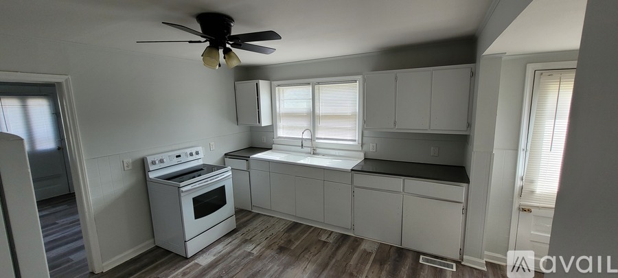 A kitchen with a white stove top oven and a fan on the ceiling.