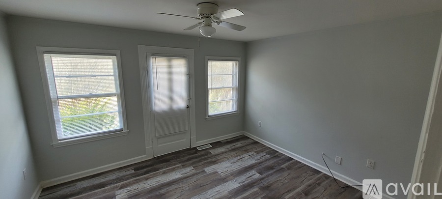 A room with a ceiling fan and three windows.