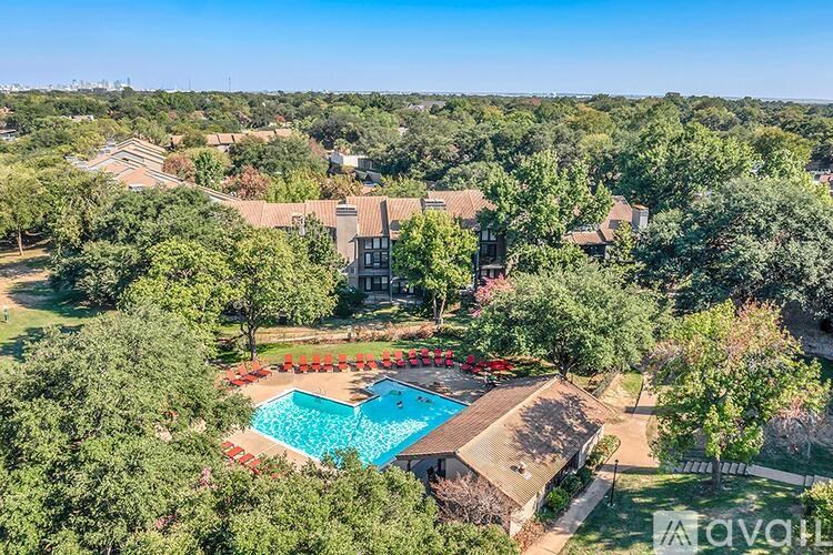 An aerial view of a house with a swimming pool surrounded by trees.
