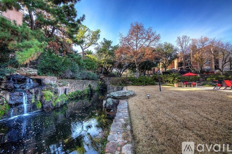A beautiful garden with a waterfall and a red umbrella.