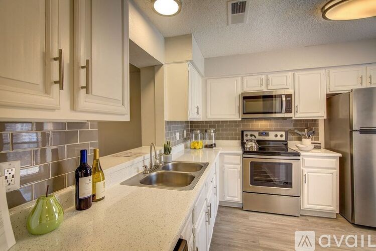 A kitchen with white cabinets and a stainless steel refrigerator.