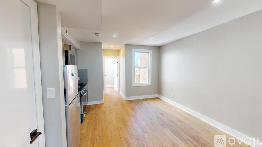 A kitchen with a refrigerator, sink, and wooden floors.