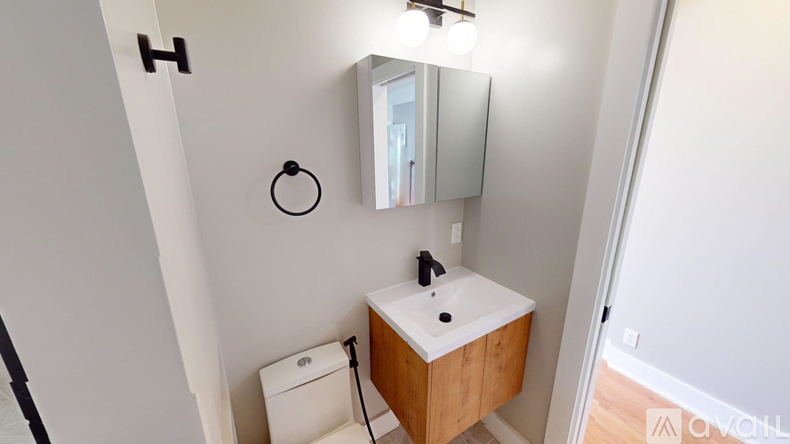 A bathroom with a sink, mirror, and toilet paper holder.