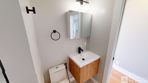 A bathroom with a sink, mirror, and toilet paper holder.