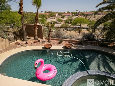 A pink flamingo float in a pool with a view of a neighborhood.