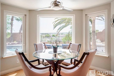 A dining room with a table and chairs and a painting on the wall.