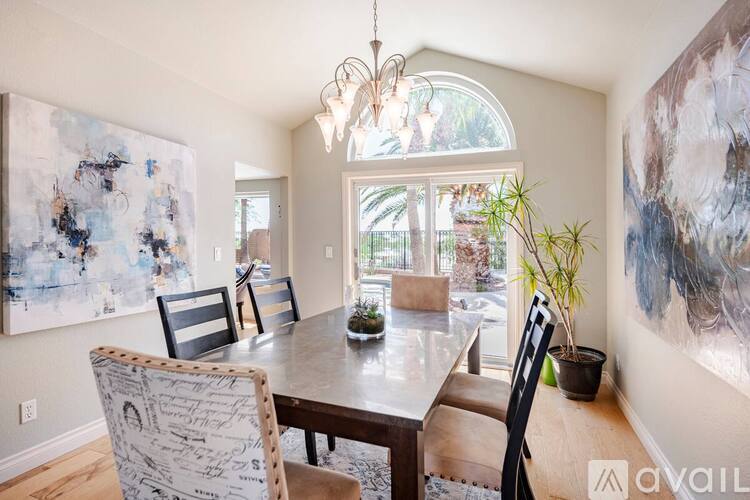 A living room with a grey couch, a round table, and a painting on the wall.
