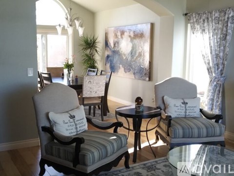 A living room with a grey couch, a round table, and a painting on the wall.