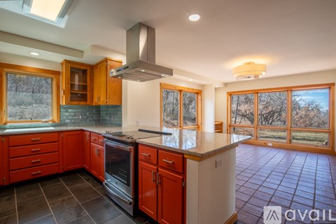 A kitchen with red cabinets and a black stove top oven.