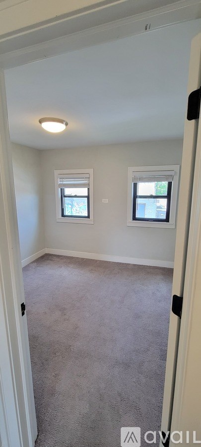 A room with carpeted floor and two windows.