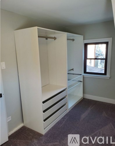 A large white closet with drawers and a window.