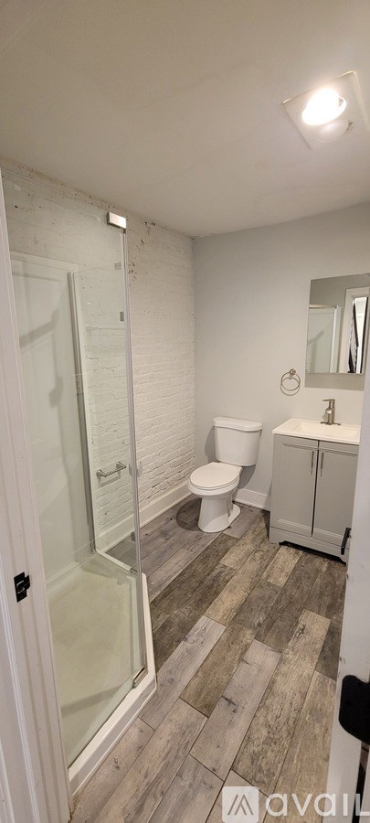 A shower with a glass door is in a bathroom with a white door.