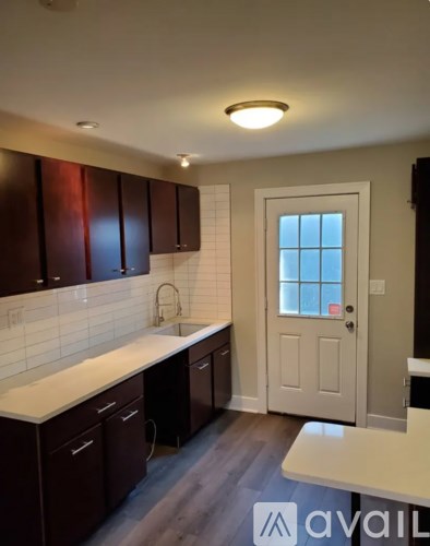 A kitchen with dark brown cabinets and a white countertop.