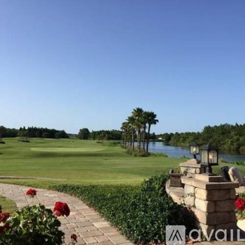 A golf course with a stone wall and flowers in the foreground.