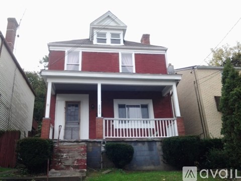 A red and white house with a balcony and a small porch.