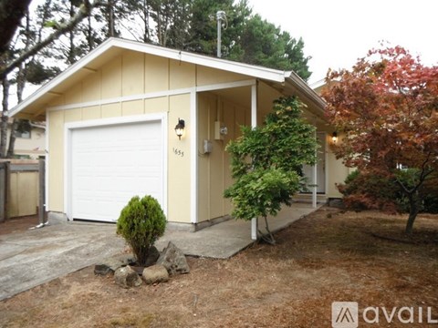 A small house with a white garage door and a brown roof.