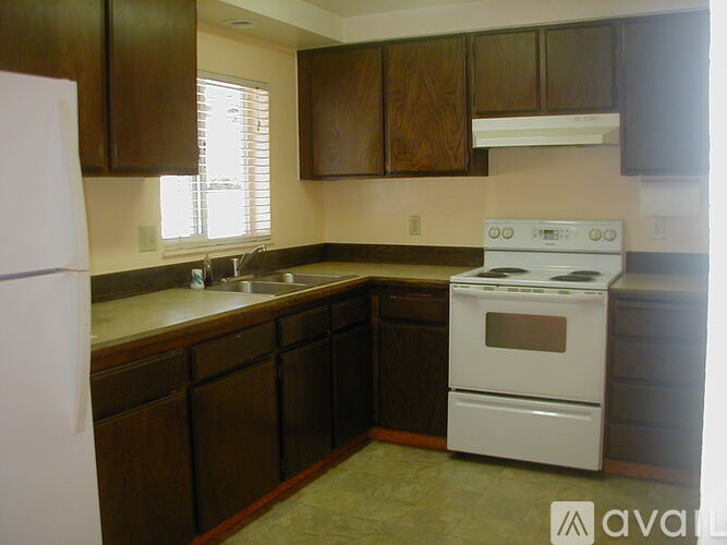 A kitchen with a white stove and wooden cabinets.