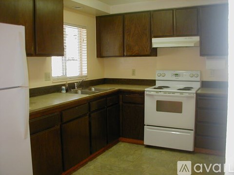 A kitchen with a white stove and wooden cabinets.