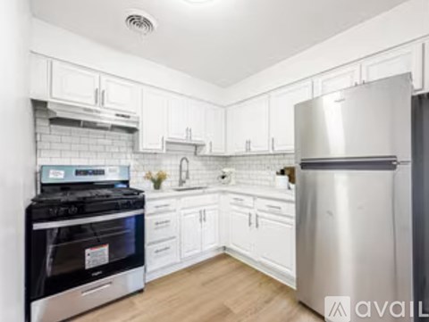 A kitchen with white cabinets and a stainless steel refrigerator.